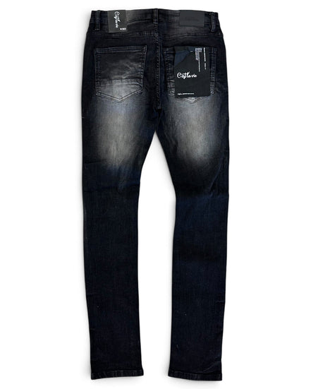Back view of a pair of dark wash skinny jeans with a faded wash on the thighs, featuring a black brand tag on the back pocket and a white inner waistband label.