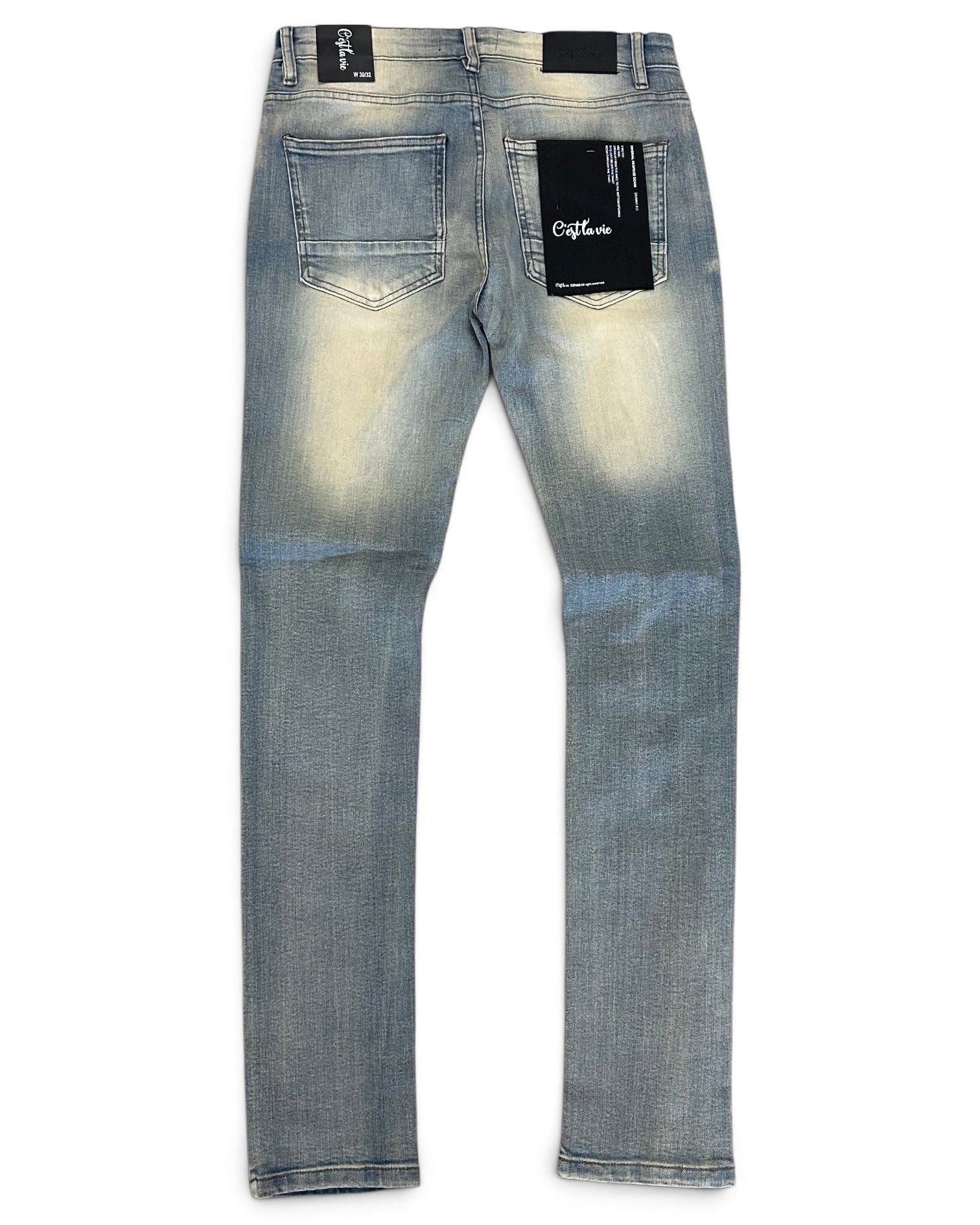 Back view of light blue denim jeans with a faded wash, featuring black brand patches on the back pockets and waistband.