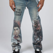 A person wearing light-wash blue jeans with large printed movie graphics and the text 'THE WORLD CHICO' on the thigh, paired with a black and purple shirt and black shoes, photographed against a light gray studio background.