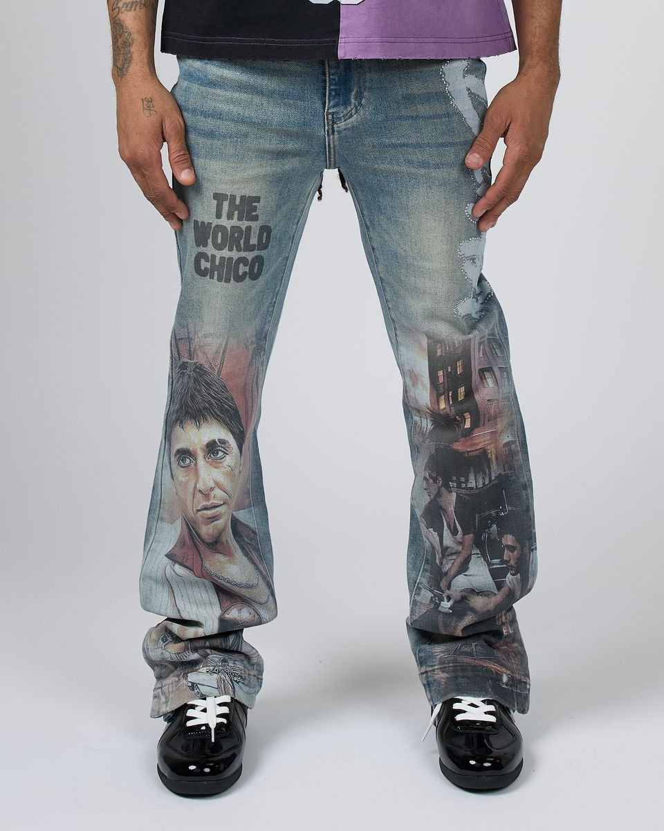 A person wearing light-wash blue jeans with large printed movie graphics and the text 'THE WORLD CHICO' on the thigh, paired with a black and purple shirt and black shoes, photographed against a light gray studio background.