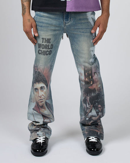A person wearing light-wash blue jeans with large printed movie graphics and the text 'THE WORLD CHICO' on the thigh, paired with a black and purple shirt and black shoes, photographed against a light gray studio background.