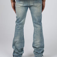 Rear view of a person wearing light-wash blue jeans with a split purple and black shirt, standing against a light gray studio background.