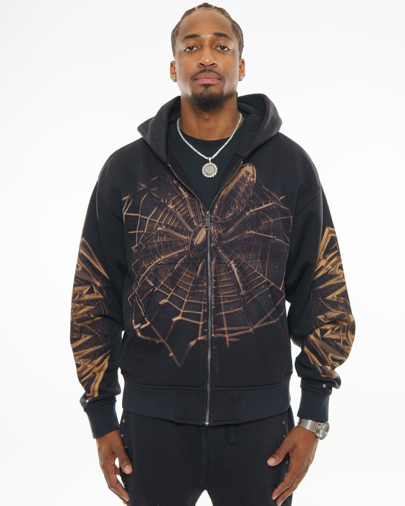 Man wearing a black hoodie with a spider web design on a white background