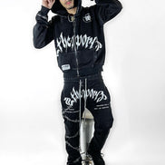 Person wearing a black hoodie and pants with white text on a white background