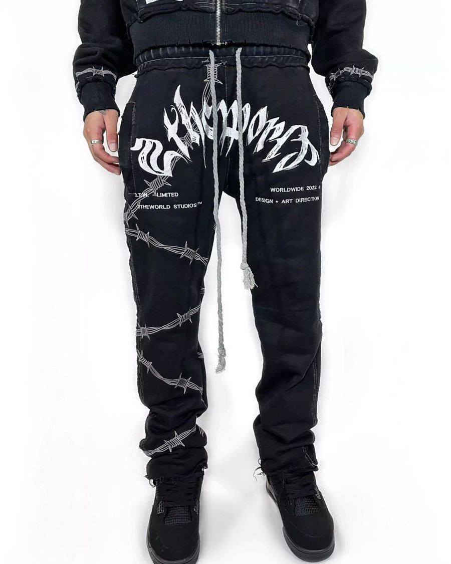 Black pants with white designs worn by a person on a white background