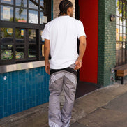 Person walking past a building with a red door and blue tiled wall.