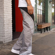 Person wearing gray pants with a pattern, standing on a sidewalk.