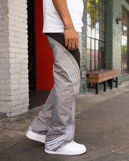 Person wearing gray pants with a pattern, standing on a sidewalk.