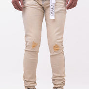 Beige distressed jeans worn by a person on a white background
