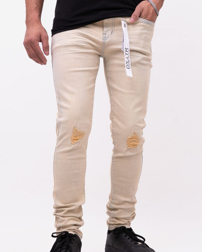 Beige distressed jeans worn by a person on a white background