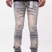Person wearing distressed light blue jeans with a visible brand label on a white background