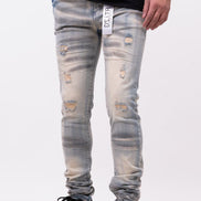 Person wearing distressed light blue jeans and black shoes on a white background