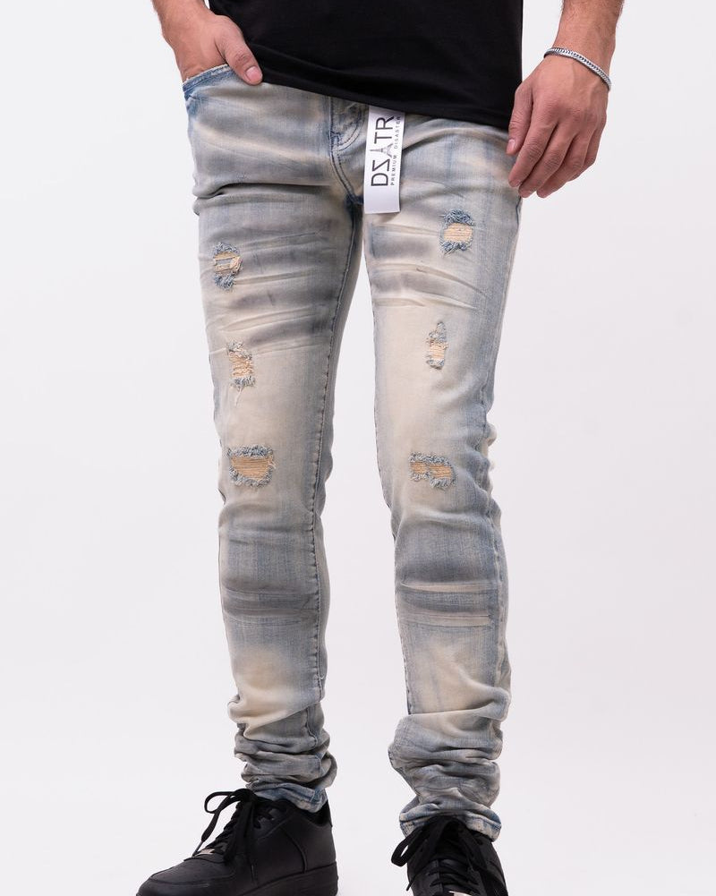 Person wearing distressed light blue jeans and black shoes on a white background