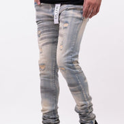 Person wearing distressed light blue jeans and black shoes on a white background