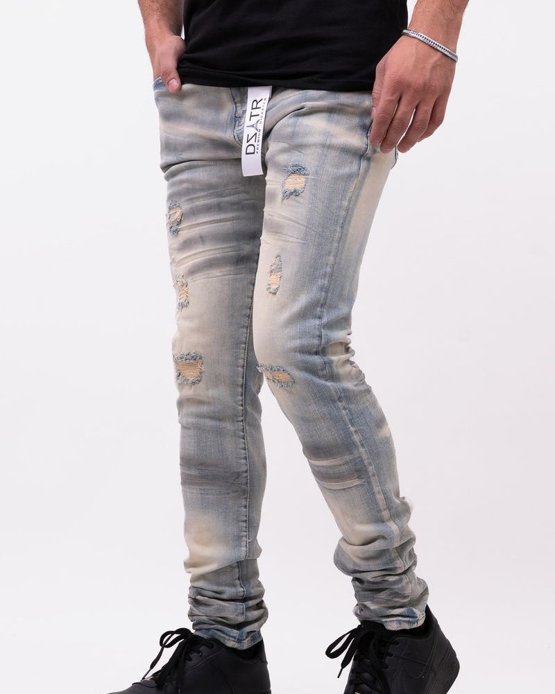 Person wearing distressed light blue jeans and black shoes on a white background