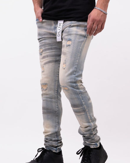 Person wearing distressed light blue jeans and black shoes on a white background