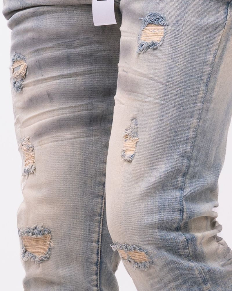 Ripped light blue jeans with a brand tag on a white background