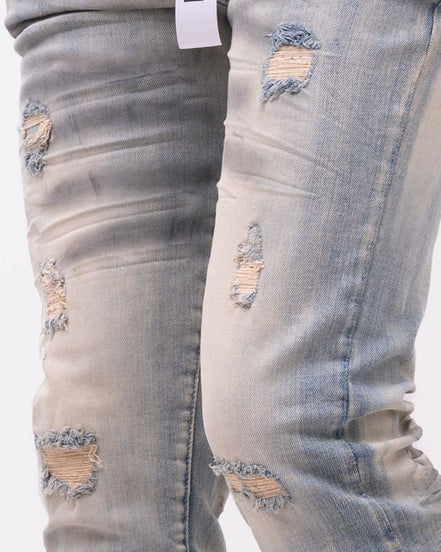 Ripped light blue jeans with a brand tag on a white background