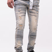 Person wearing distressed light blue jeans with a brand tag on a white background