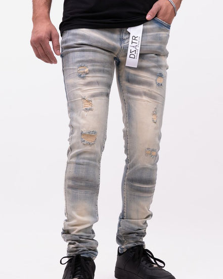 Person wearing distressed light blue jeans with a brand tag on a white background