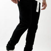 Person wearing black jogger pants with a brand logo on a white background