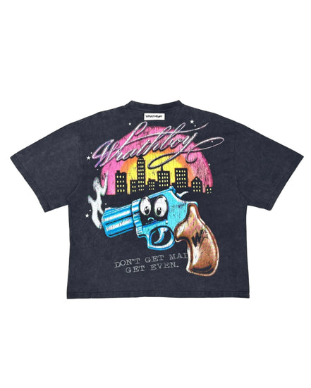 A dark black graphic t-shirt featuring a cartoon-style blue revolver with a surprised face, a brown gun handle, and a pink and yellow city skyline under the word 'Wanted' in white script.