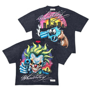 Two black graphic t-shirts featuring a colorful cartoon clown and a blue gun with a pink and yellow city skyline print, displayed against a white background.