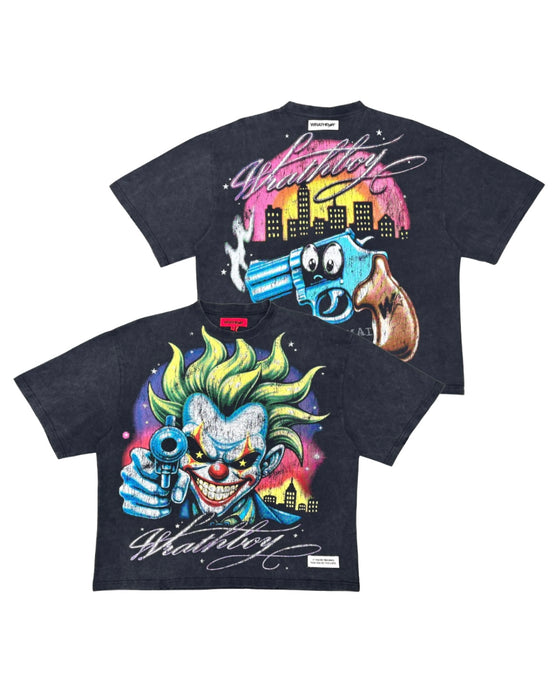 Two black graphic t-shirts featuring a colorful cartoon clown and a blue gun with a pink and yellow city skyline print, displayed against a white background.