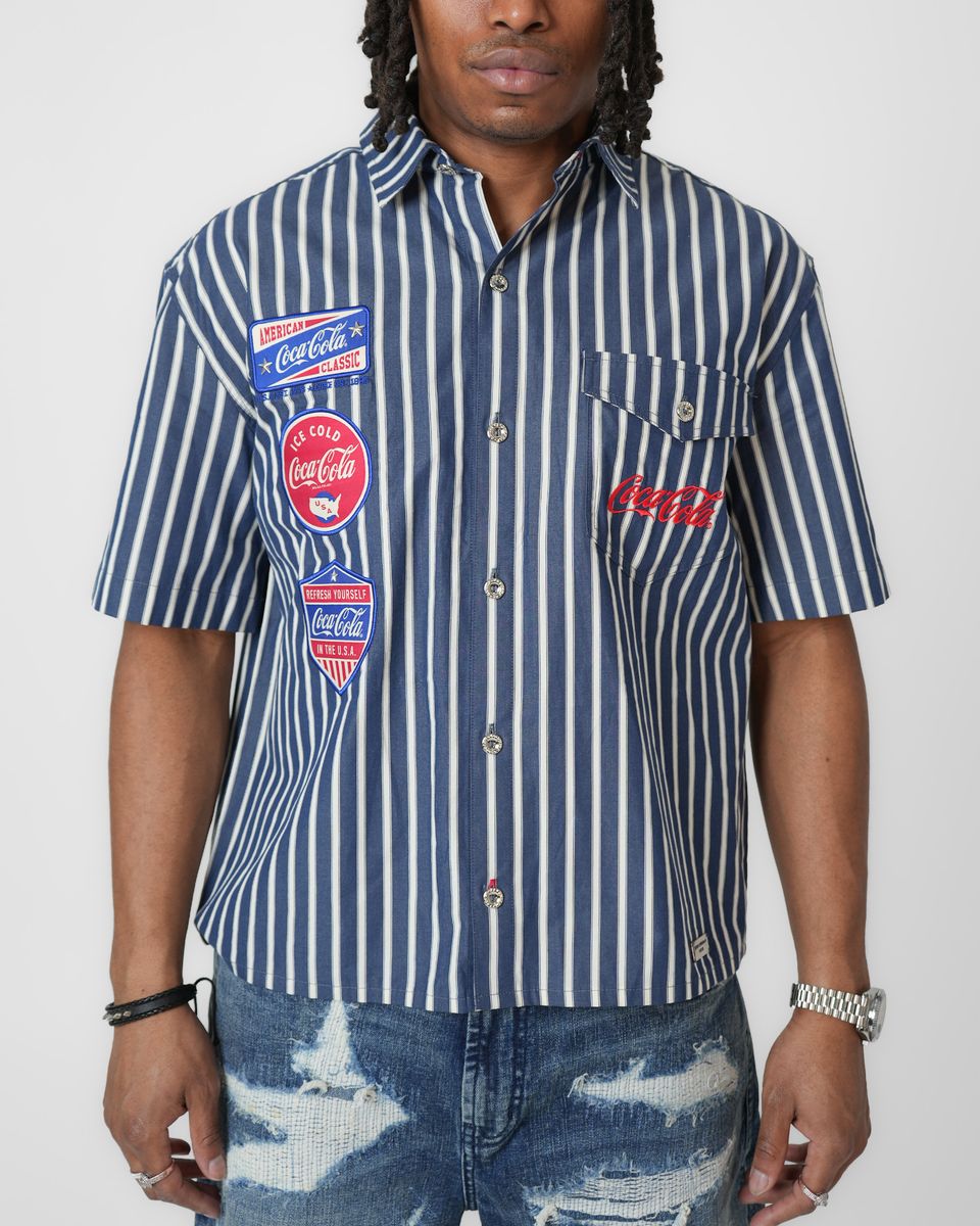 Person wearing a blue and white striped shirt with Coca-Cola logos on a white background