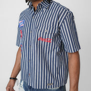 Person wearing a navy and white striped shirt with Coca-Cola logo on a plain background