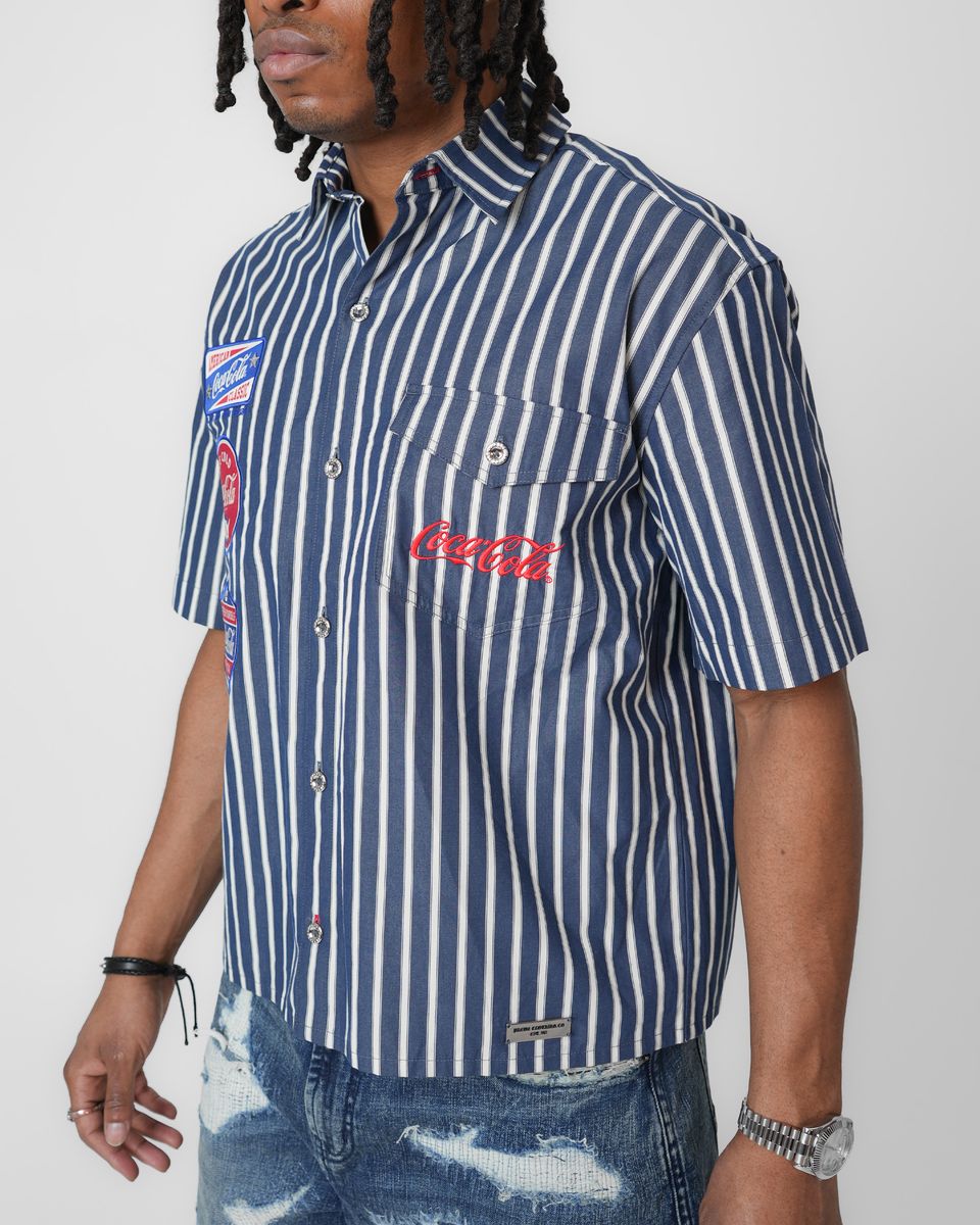 Person wearing a navy and white striped shirt with Coca-Cola logo on a plain background