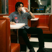 Person sitting in a diner booth, drinking from a cup.