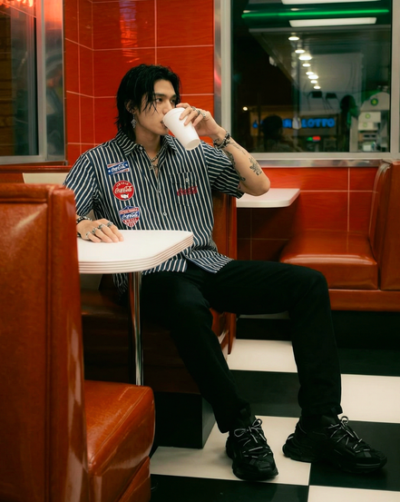 Person sitting in a diner booth, drinking from a cup.