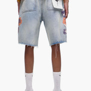 Person wearing light blue denim shorts with colorful patches on a white background