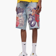 Person wearing colorful graphic shorts with a yellow top and white sneakers on a white background