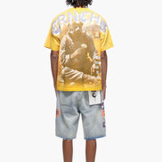 Person wearing a yellow graphic t-shirt and denim shorts on a white background