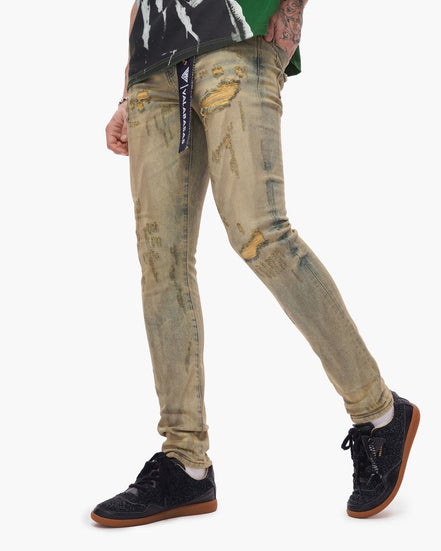 Person wearing distressed beige jeans with a visible brand label on a white background
