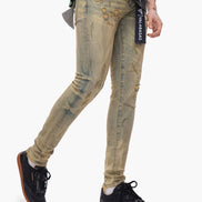 Person wearing distressed beige jeans with a brand label on a white background