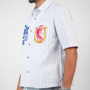 Man wearing a white striped shirt with colorful graphics and text on a plain background