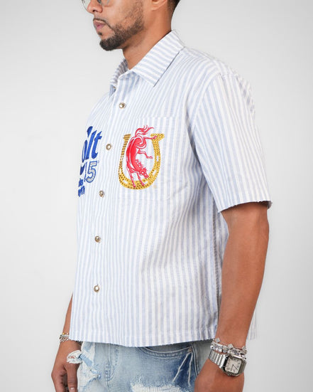 Man wearing a white striped shirt with colorful graphics and text on a plain background