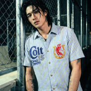 Person wearing a striped shirt with brand logos in an outdoor setting