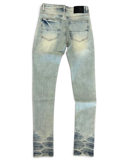 Light wash blue denim jeans shown from the back, featuring a faded yellowish tint on the thighs and a dark blue tie-dye pattern at the hem.