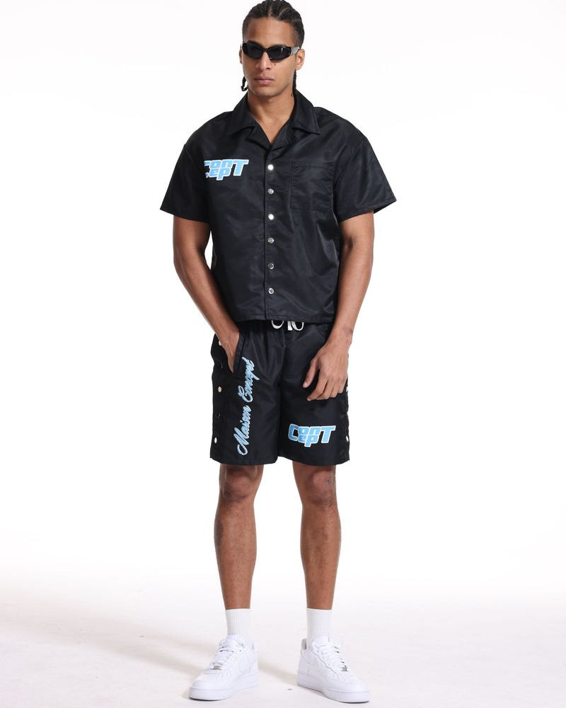 Person wearing a black shirt and shorts with logos on a white background