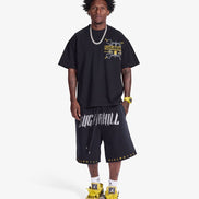 Person wearing a black graphic t-shirt and shorts with visible branding on a white background