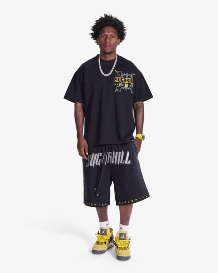 Person wearing a black graphic t-shirt and shorts with visible branding on a white background