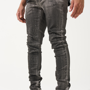 Person wearing gray distressed jeans and black and white sneakers on a white background