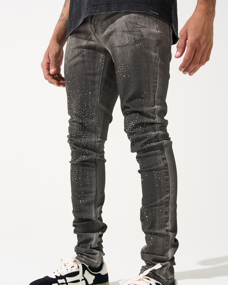 Person wearing gray distressed jeans and black and white sneakers on a white background