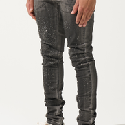 Person wearing black jeans with white speckles and black and white sneakers on a white background
