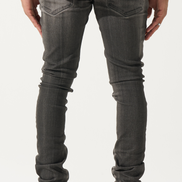 Person wearing dark gray jeans and black and white sneakers on a white background