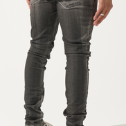 Person wearing dark gray jeans and black and white shoes on a white background